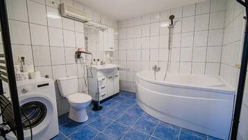 A bathroom with a washing machine, toilet, sink, and bathtub.