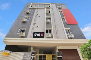 Ein mehrstöckiges Hotelgebäude mit Klimaanlagen an jeder Etage, einem markanten roten Abschnitt an der Fassade und einem Schild, das angibt, dass es sich um ein OYO Hotel RBS ECIL handelt.