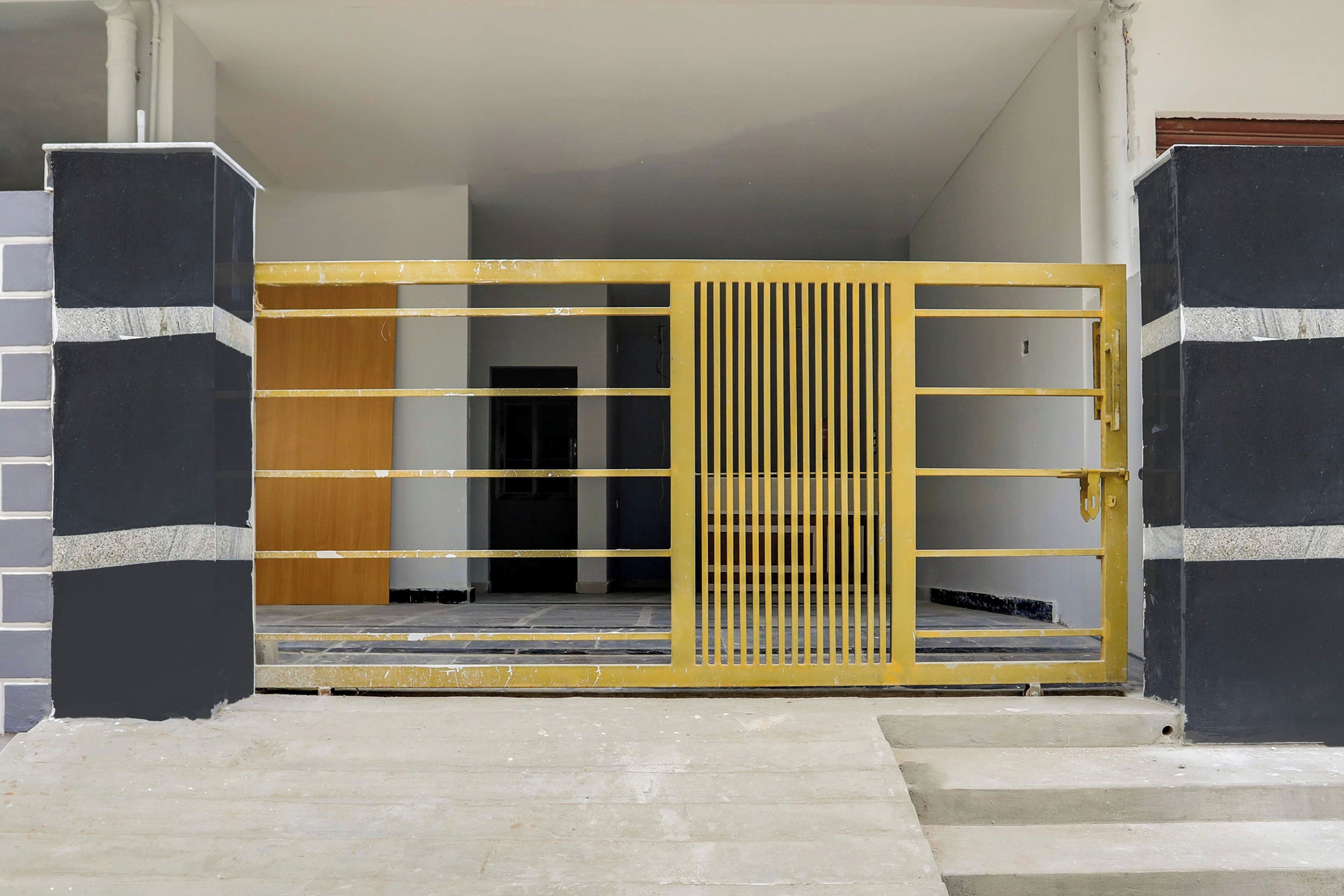 A gated entrance with a yellow metal gate and a staircase leading to a dark interior.