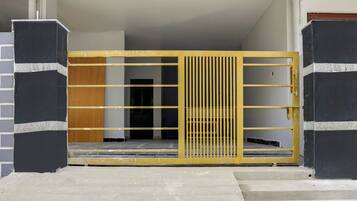 A gated entrance with a yellow metal gate and a staircase leading to a dark interior.