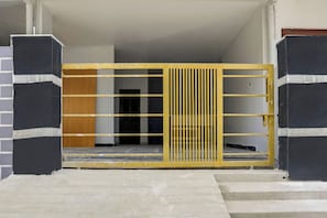 Ein begrenzter Eingangsbereich mit einem gelben Metalltor und einer Treppe, die zu einem dunklen Innenraum führt.