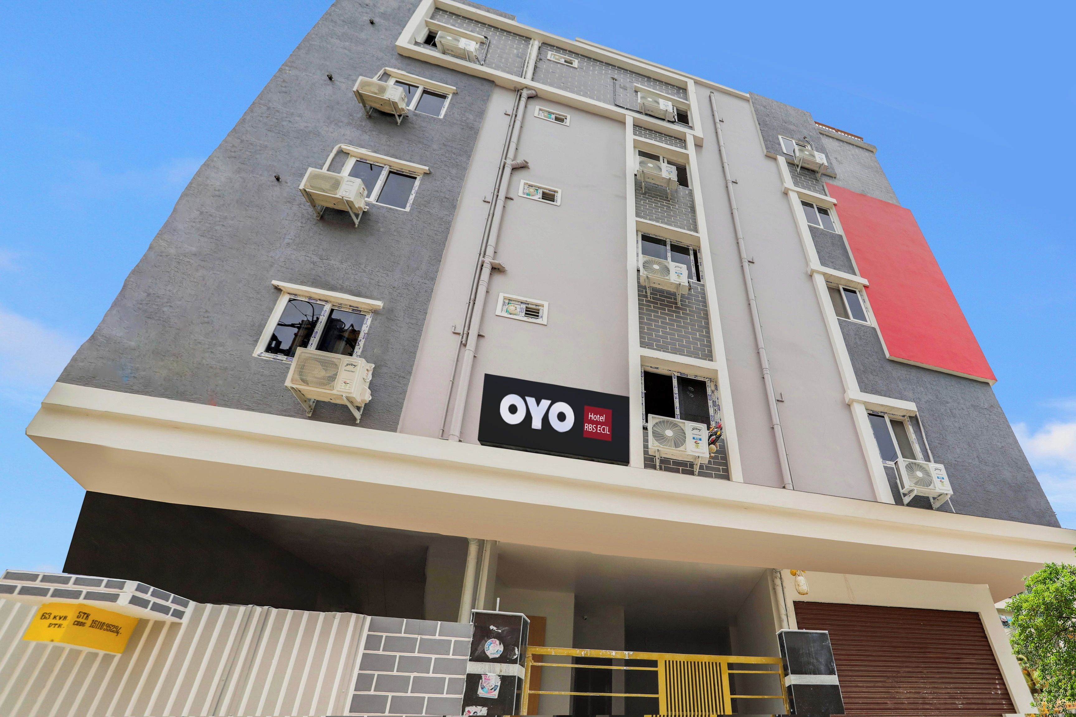Un edificio de hotel de varios pisos con balcones, unidades de aire acondicionado y un letrero destacado que dice 'OYO Hotel RBS ECIL'.
