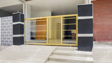 Una entrada protegida con un portón metálico, varios escalones de concreto y un muro de ladrillo.