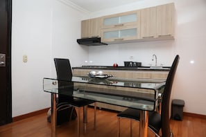 Una cocina moderna con una mesa de vidrio, sillas negras y armarios de madera.