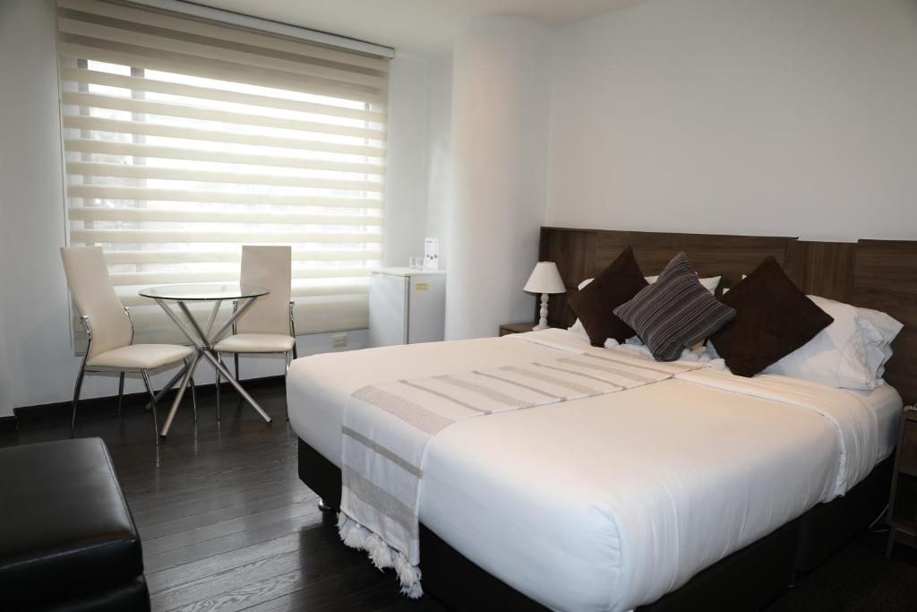A hotel room with a bed, a small table, a chair, and a lamp.