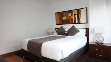 Quarto de hotel com cama, mesas de cabeceira, um quadro na parede e um tapete.