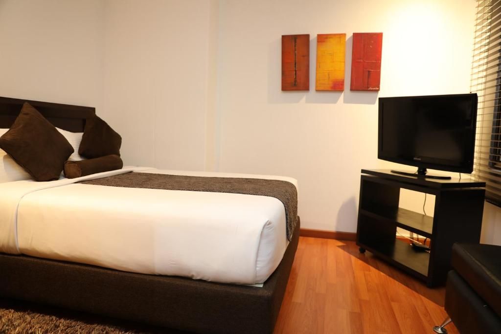 Ein Hotelzimmer mit einem Bett, einem Fernseher auf einem Schrank und Kunstwerken an der Wand.