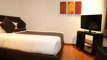 Ein Hotelzimmer mit einem Bett, einem Fernseher auf einem Schrank und Kunstwerken an der Wand.