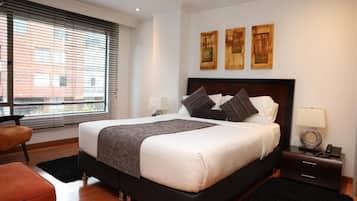 Una habitación de hotel con una cama grande, una mesita de noche, una silla y una obra de arte en la pared.