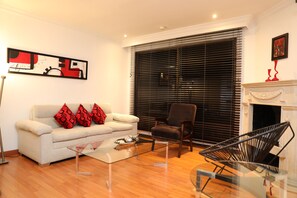 A modern living room with a sofa, armchair, and a glass coffee table. - Hotel Suites 108 (Bogotá)