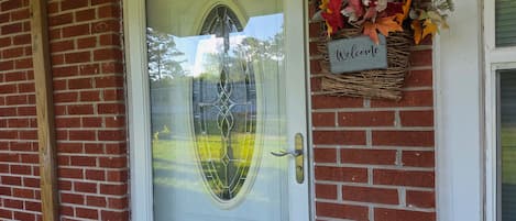 A white door with a glass panel and a 'Welcome' sign above it.