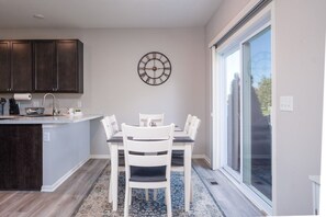 Una cocina moderna con comedor, un reloj en la pared y un amplio ventanal.