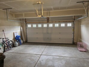 A garage with a closed garage door, a bicycle, a mop, and some cleaning supplies.