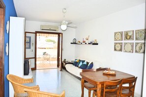 A room with a dining area, a sofa, a ceiling fan, and a door leading to an outdoor space. - Turchese Vicino Taormina e Alla Spiaggia (Giardini Naxos)
