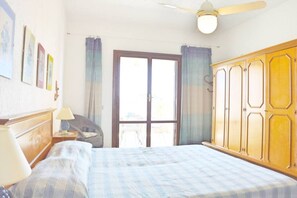 A bedroom with a bed, a wardrobe, a chair, a lamp, and a window with curtains. - Turchese Vicino Taormina e Alla Spiaggia (Giardini Naxos)