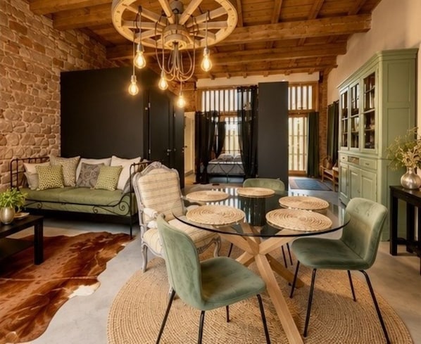 A cozy living room with a leather sofa, a glass coffee table, and a rustic wooden ceiling.