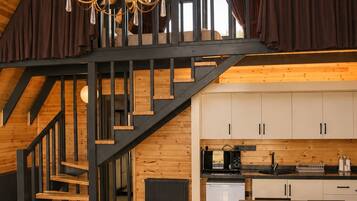 Un interior moderno estilo loft con una escalera de madera, una zona de comedor y una cocina.