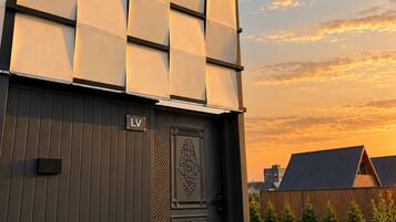 Un edificio moderno con fachada oscura, una puerta grande de diseño intrincado y un cartel con el letrero 'LV'.