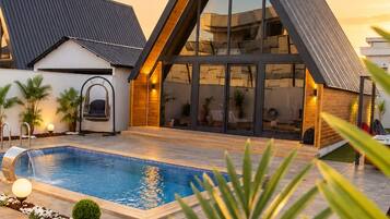 Una casa moderna con piscina, amplias ventanas y techo inclinado.