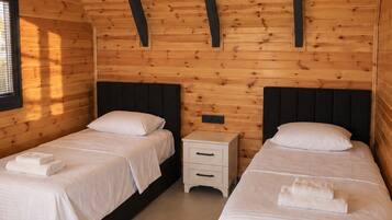 A room with two beds, a nightstand, and a window.