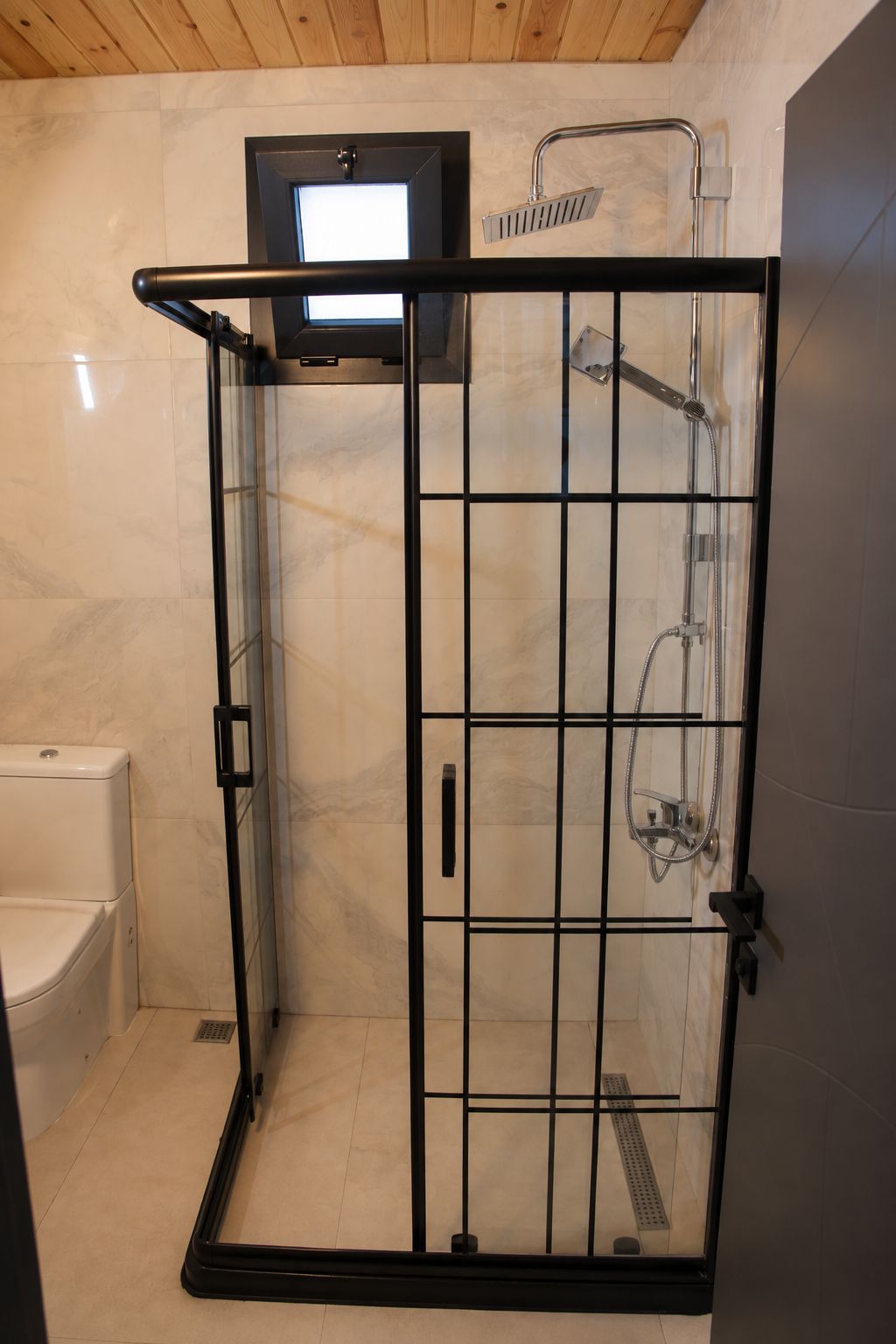 A shower enclosure with a glass door, a handheld showerhead, and a wall-mounted faucet.