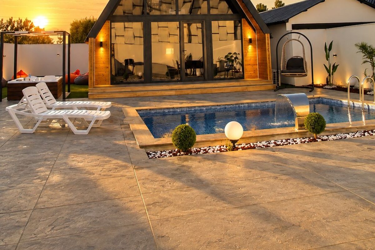A modern house with a large glass facade, a swimming pool, and outdoor seating.