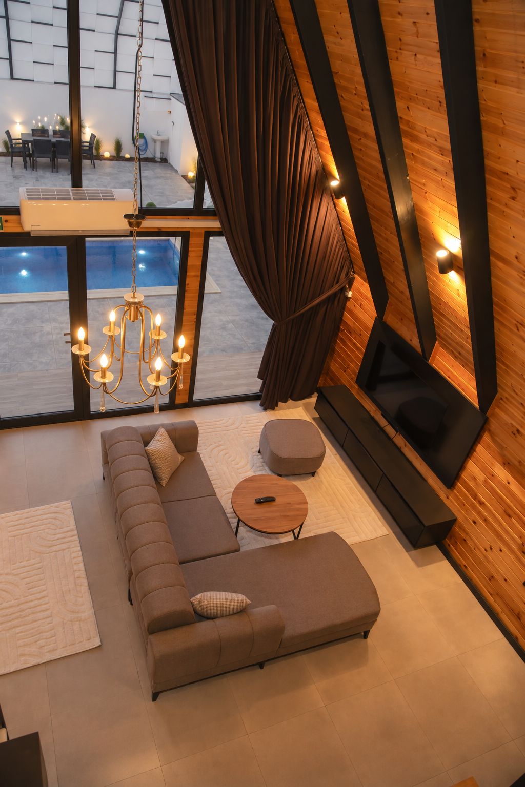 A modern living room with a sectional sofa, a round coffee table, and a large window with curtains.