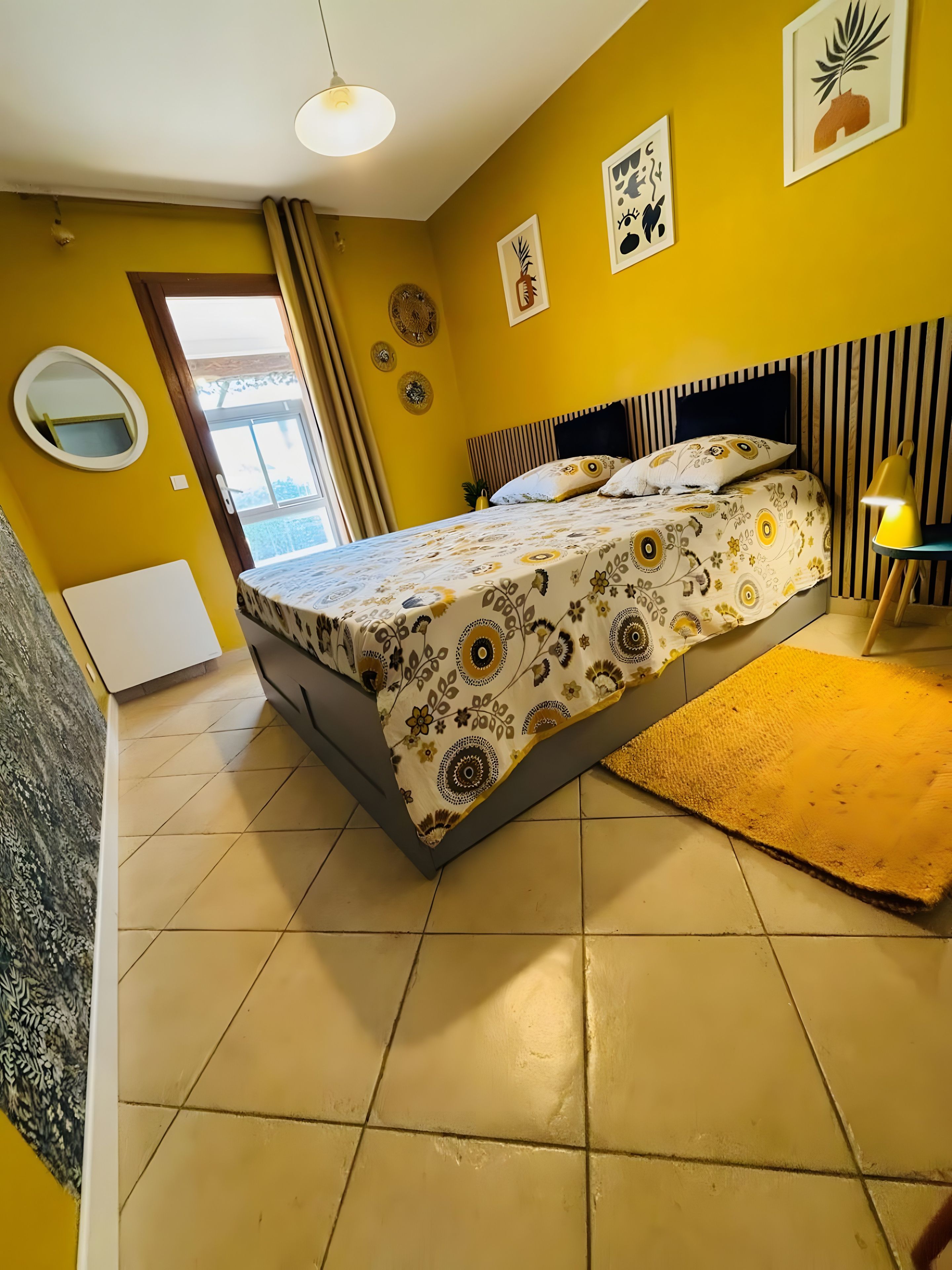Une chambre à coucher avec un lit, une lampe de chevet et une fenêtre.