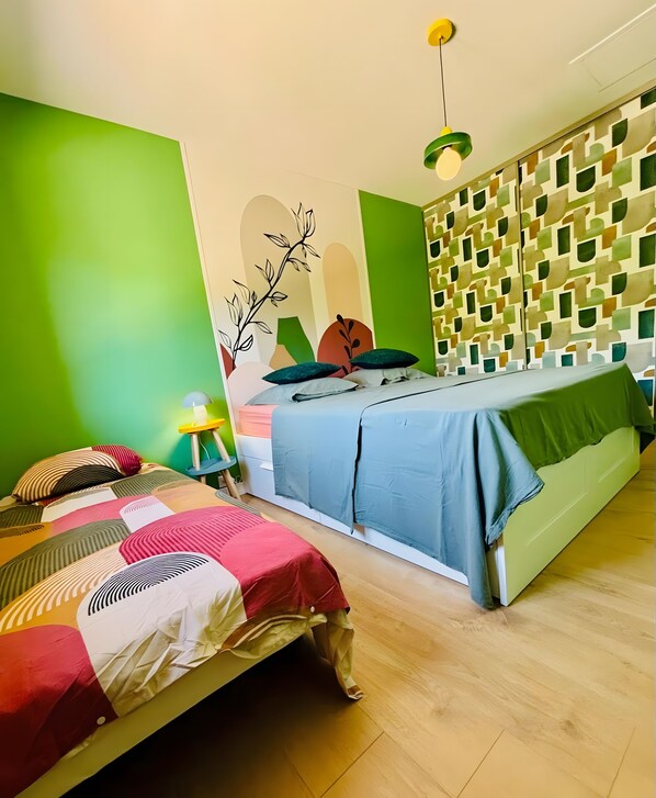A room with two beds, a green wall, and a patterned wall.