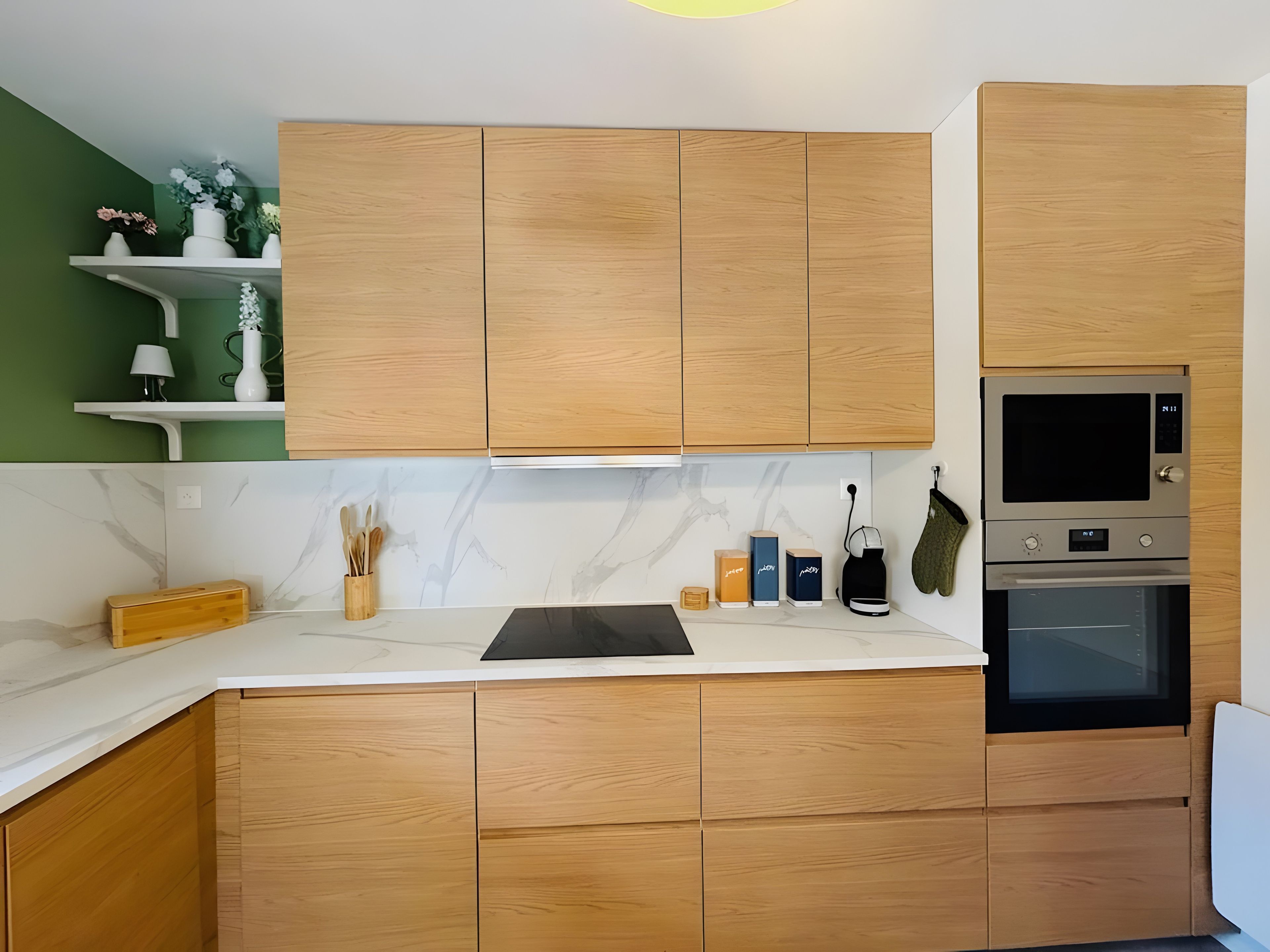 Una cucina moderna con mobili in legno, forno integrato e schienale in marmo.
