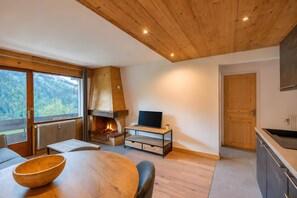 Ein modernes Interieur mit Kamin, Holzmöbeln und Blick ins Freie.