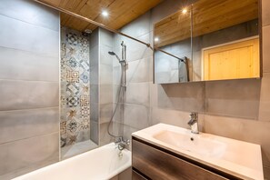 A modern bathroom with a bathtub, a shower, and a vanity with a sink. - Apartment 'Soladret' with Mountain View and Balcony (La Clusaz)