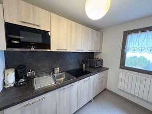 A modern kitchen with light wood cabinets, a black countertop, and a Siemens microwave. - Apartment with south-facing balcony, mountain view - 6 guests (Auris)