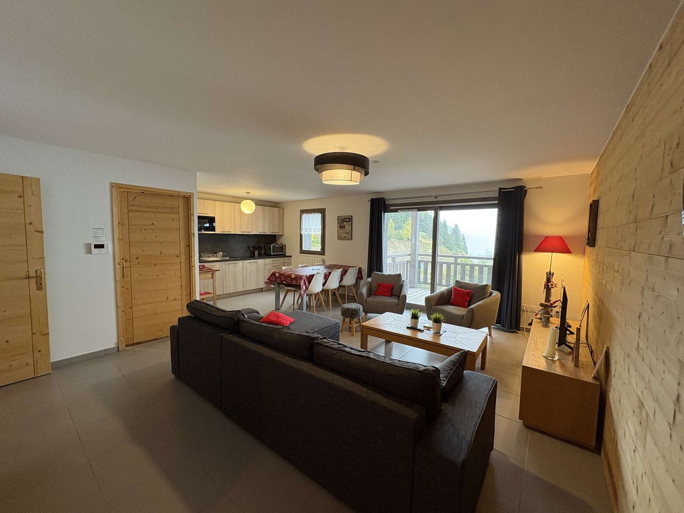 A modern living room with a sofa, a dining table, and a kitchen in the background.