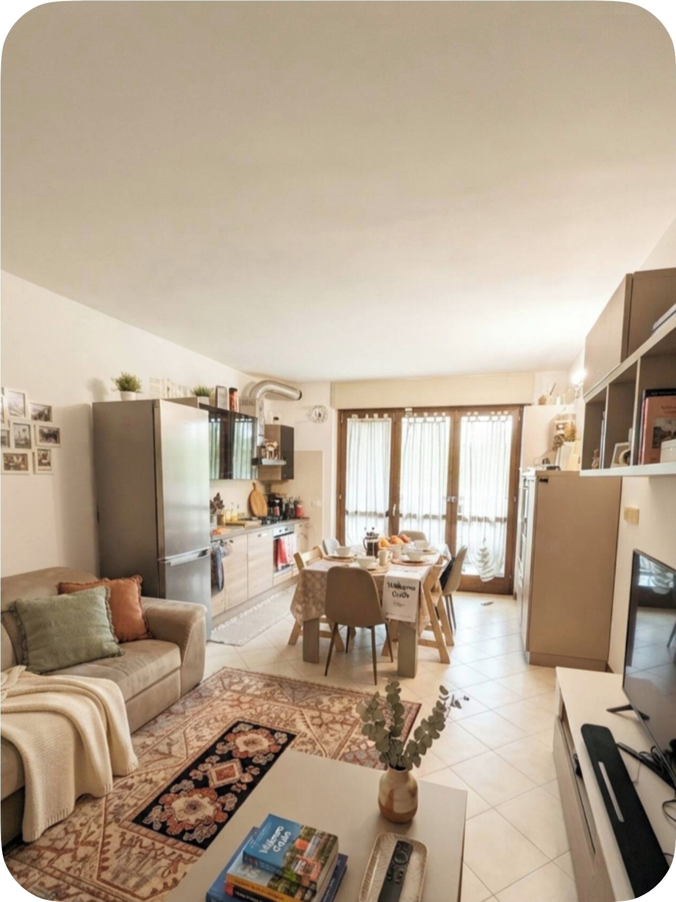 Un ambiente compatto con angolo cottura, zona pranzo e divano con tavolino.