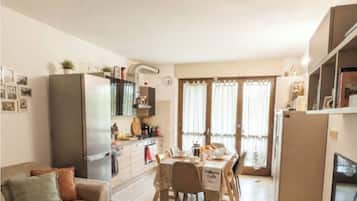 Un ambiente compatto con angolo cottura, zona pranzo e divano con tavolino.