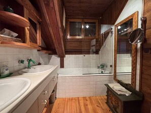 A bathroom with wooden beams, a double sink, a bathtub, and a mirror. - Charming chalet mountain view - 12 guests (Villard-de-Lans)