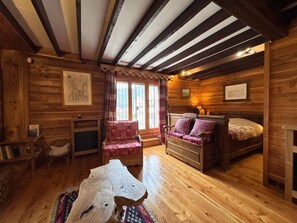 A cozy log cabin room with a bed, a chair, a wooden coffee table, and a fireplace. - Charming chalet mountain view - 12 guests (Villard-de-Lans)