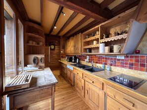 A wooden kitchen with a wooden countertop, a sink, and a stove. There are shelves with dishes and a clock on the wall. - Charming chalet mountain view - 12 guests (Villard-de-Lans)
