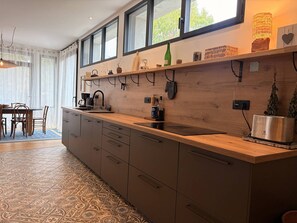 Eine moderne Küche mit Holzausziehtisch, eingebauten Schränken und einem Fenster mit Blick auf einen Garten.