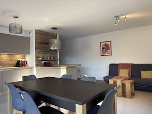 A modern kitchen with a dining area, a sofa, and a coffee machine. - Spacious apartment in the heart of Vercors - 6 guests (Villard-de-Lans)