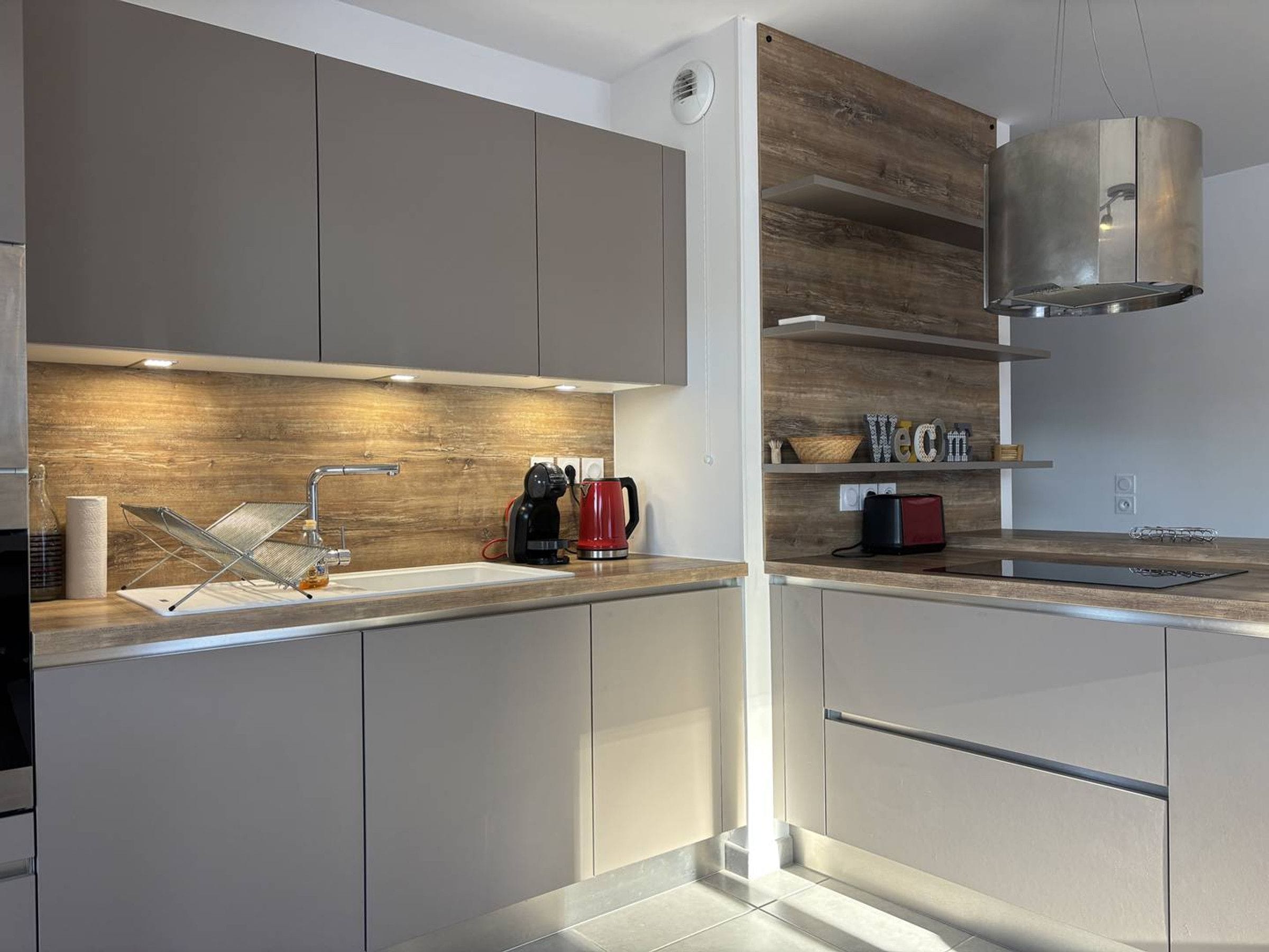 A modern kitchen with a wooden backsplash, stainless steel appliances, and a built-in oven.