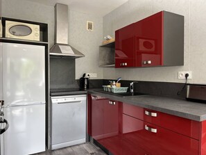 Une cuisine compacte équipée d’un réfrigérateur, d’un lave-vaisselle et d’un four à micro-ondes posé sur le plan de travail.