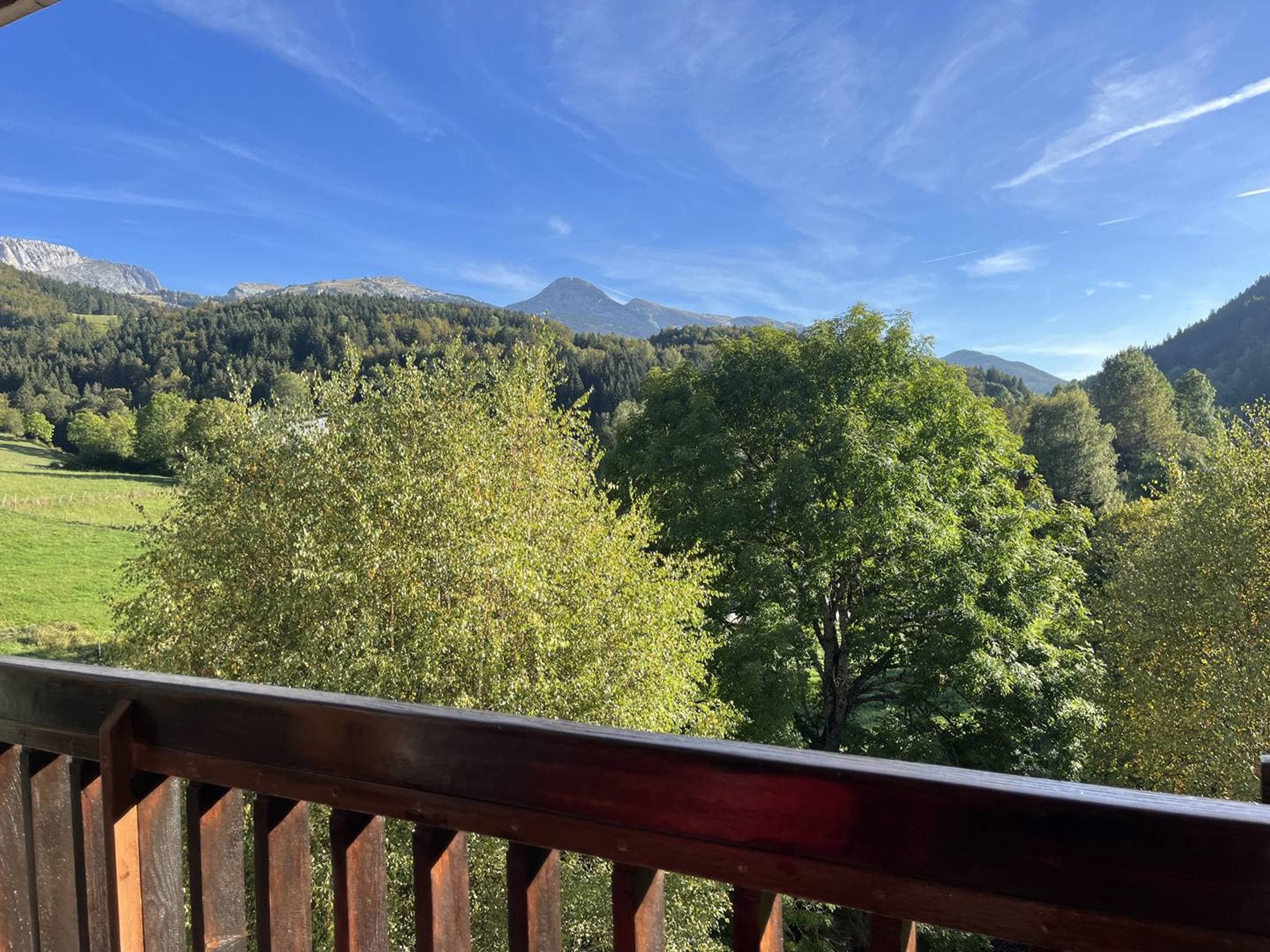 Ein Balkon mit Blick auf eine gebirgige Landschaft, Bäume und einen klaren Himmel.