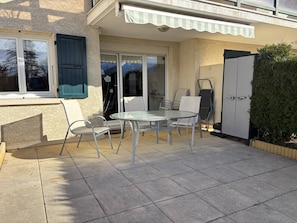 A patio with a round table and chairs, a sliding glass door, and a small garden area. - Apartment with mountain view - 4 guests (Villard-de-Lans)