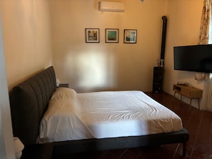 A bedroom with a bed, a television, and three framed pictures on the wall. - Villa Cabu Abbas (Perfugas)