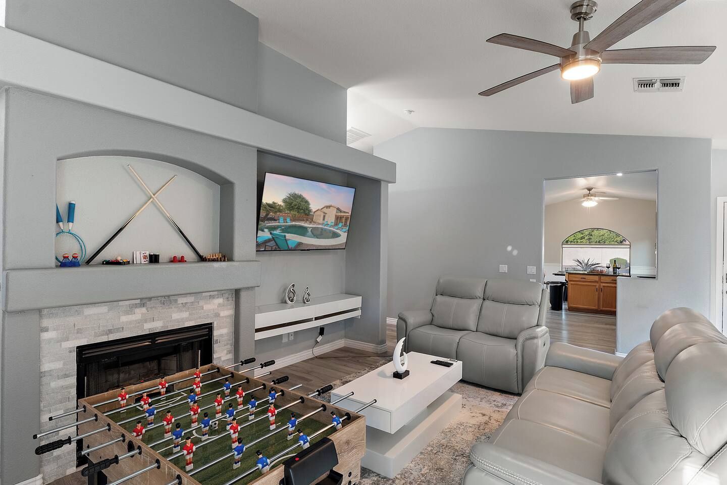 A modern living room with a foosball table, a fireplace, a television, and a seating area.