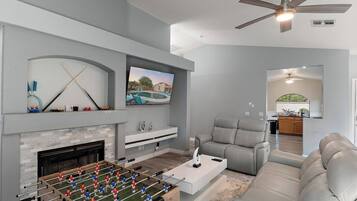 A modern living room with a foosball table, a fireplace, a television, and a seating area.