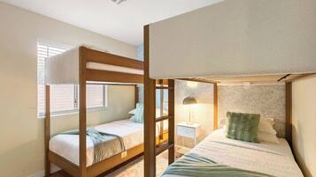 Habitación con literas, una mesita de noche con lámpara y pared con diseño.
