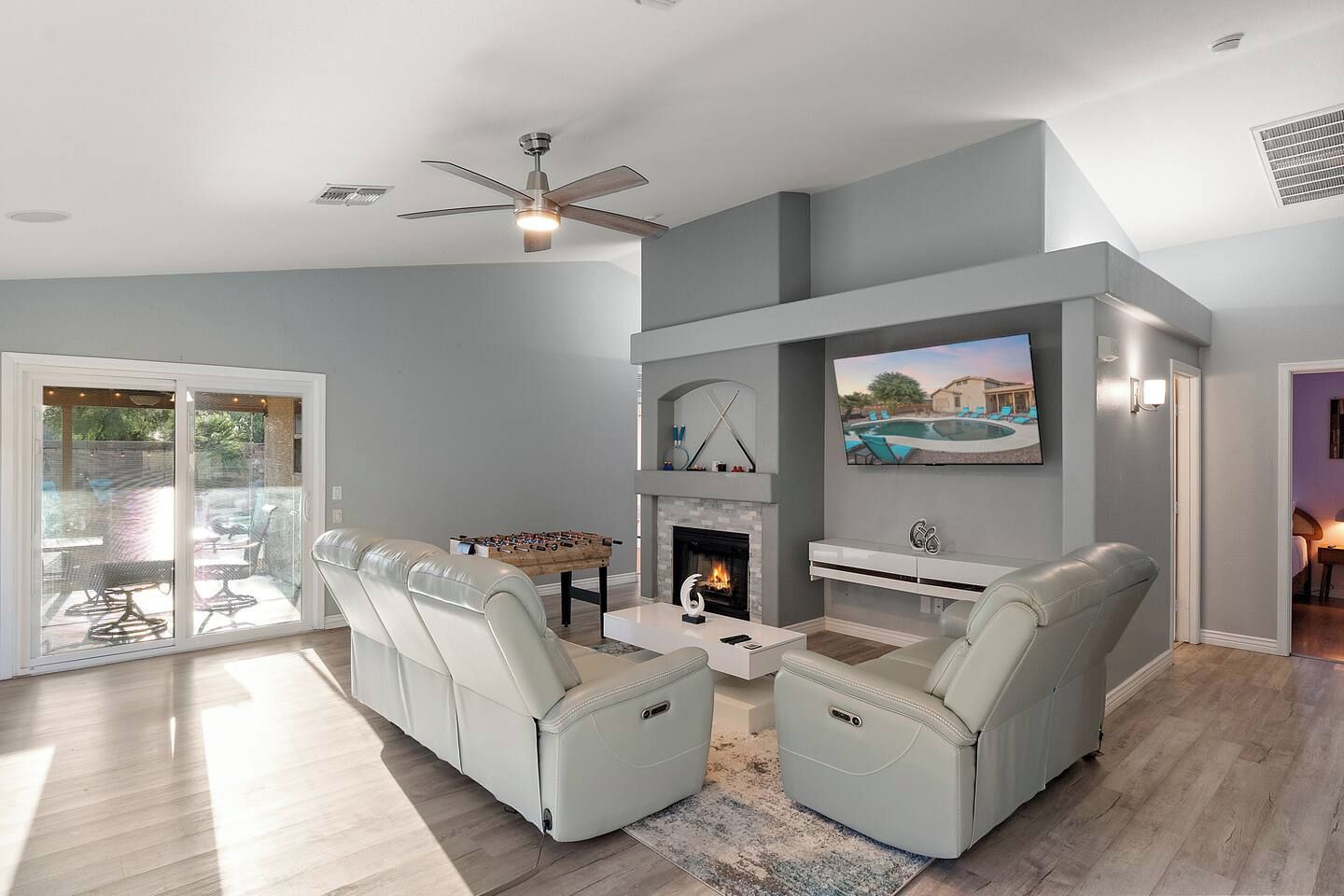 A modern living room with a fireplace, a television mounted above it, and a sofa set.